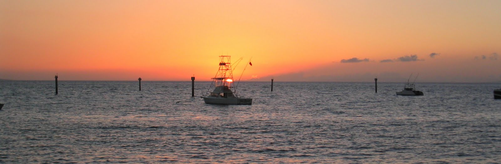 Fishing boats silhouetted against an orange sunset