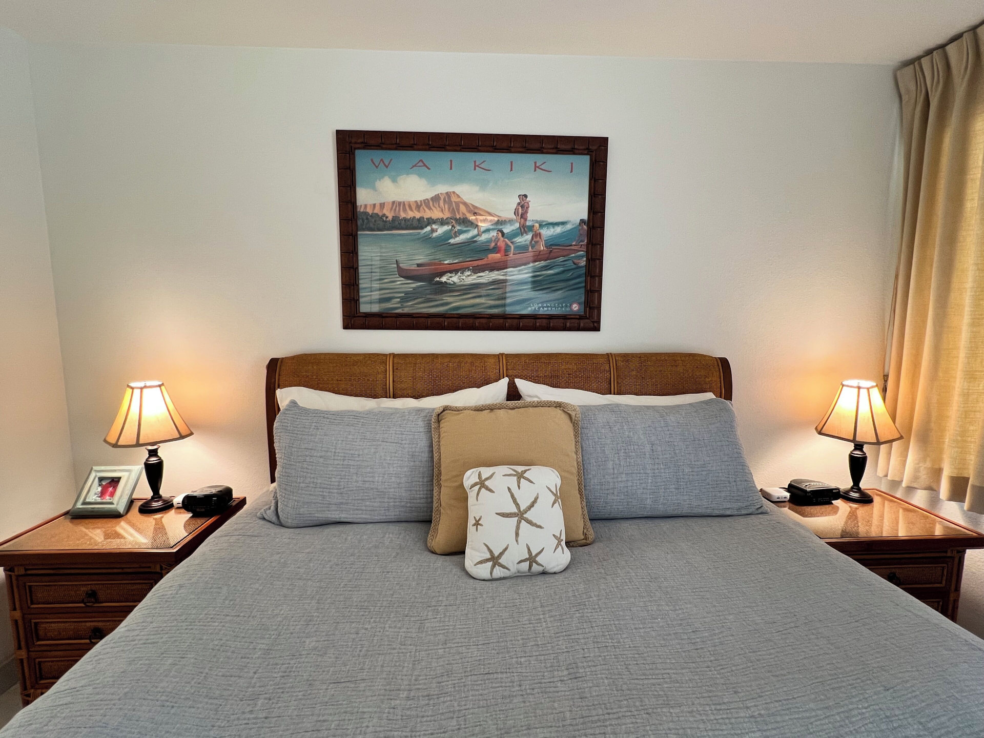 King bed with bedside lamps and coastal artwork