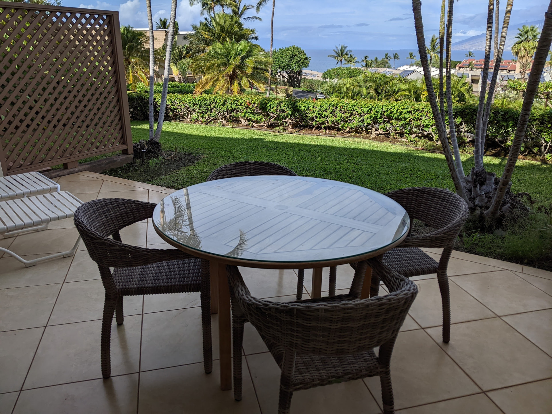 Lanai dining table overlooking tropical grounds and the ocean